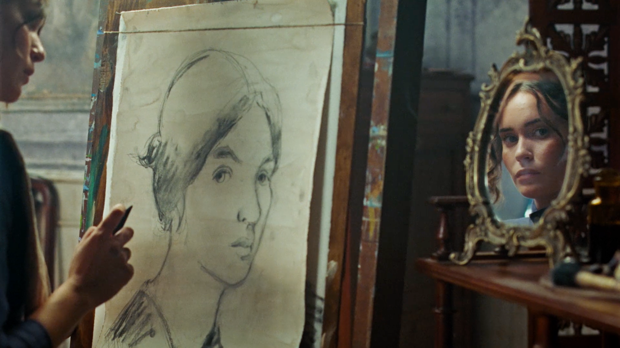 Desenho de um retrato no cavalete, ao lado do rosto de uma mulher refletido em um espelho ornamentado.