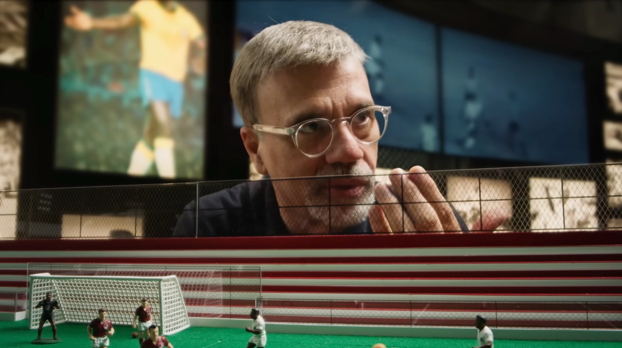 Homem observando a maquete do campo de futebol.