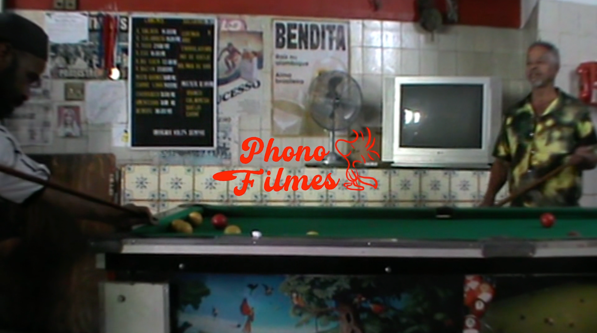 Mesa de sinuca e interior do bar, com a marca Phono Filmes em vermelho.