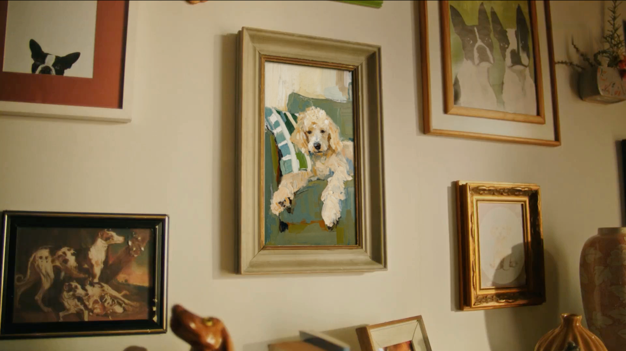 Quadros na parede da sala, com um retrato de cachorro em destaque.